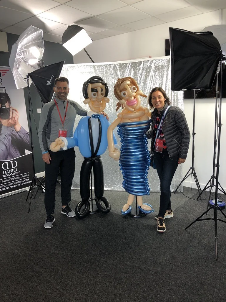 A couple posing beside life-size balloon figures at an exhibition