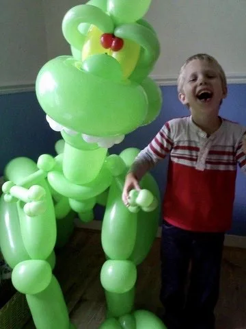 A laughing child beside a giant green balloon creature