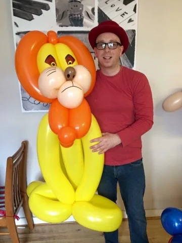 Benny standing beside a bright orange and yellow life-size balloon character