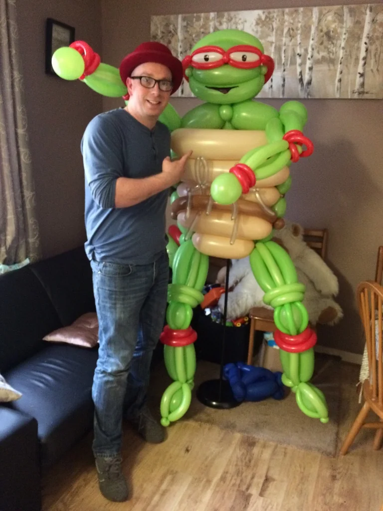 Benny standing beside a large green life-size balloon character