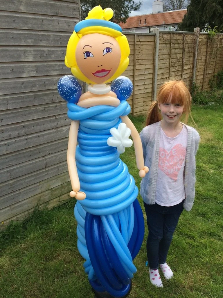 A child standing beside a large princess balloon creation