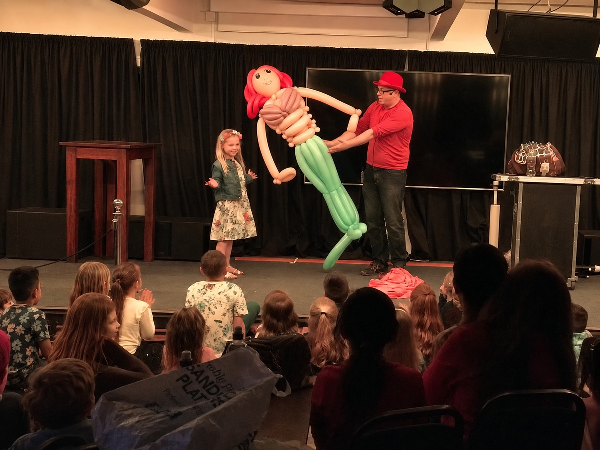 Birthday child with a life-size balloon creation on stage