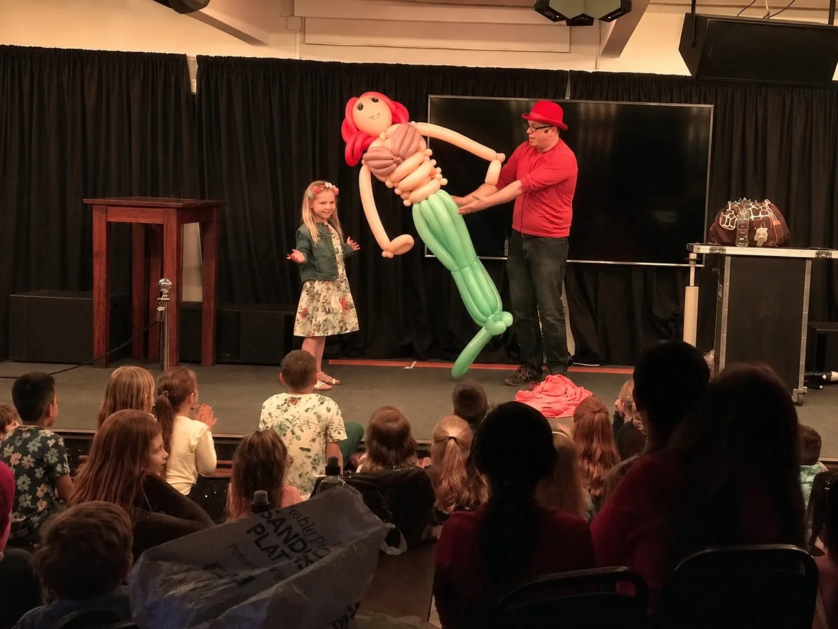 Birthday child with a life-size balloon creation on stage