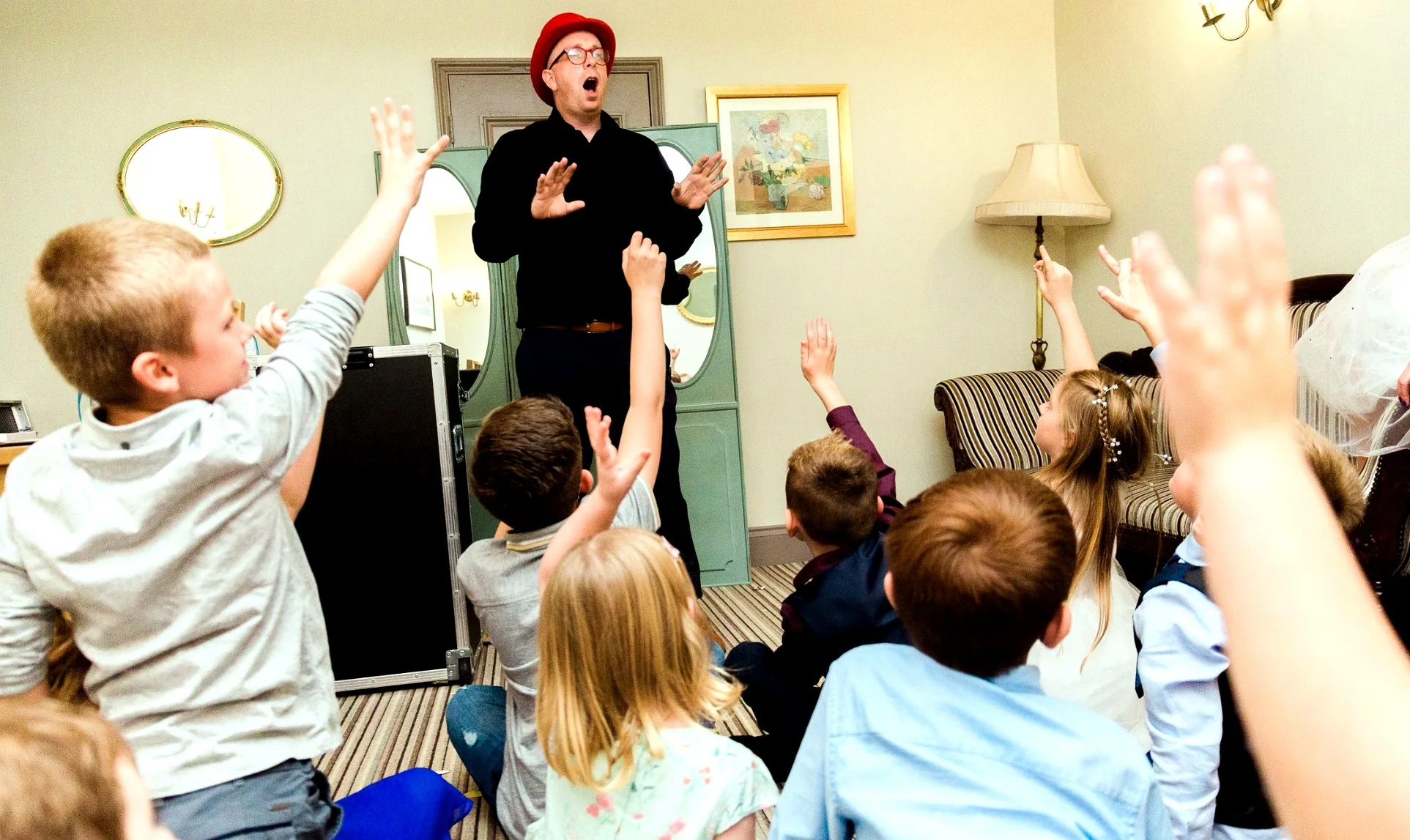 Children raising their hands and joining in with Benny’s comedy magic show
