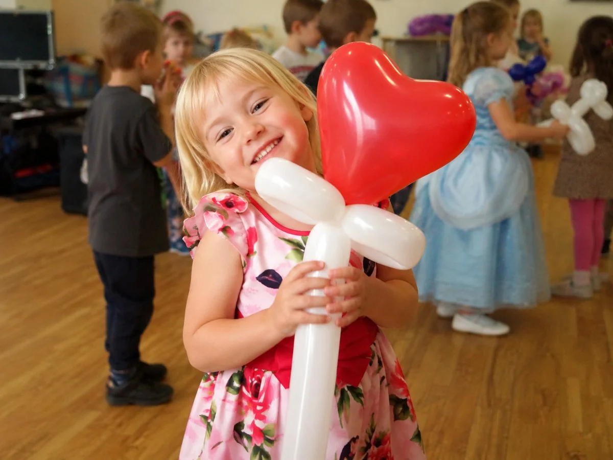 A child proudly holding a balloon creation after the party