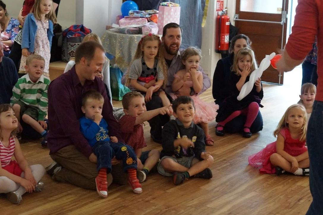 Children and parents smiling while watching Benny perform